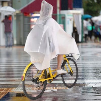FEMME PEDALANT AVEC CAPE DE PLUIE VELO SUR ROUTE