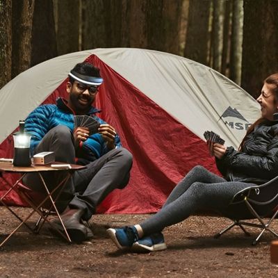 Couple joue cartes bivouac lampe frontale heureux