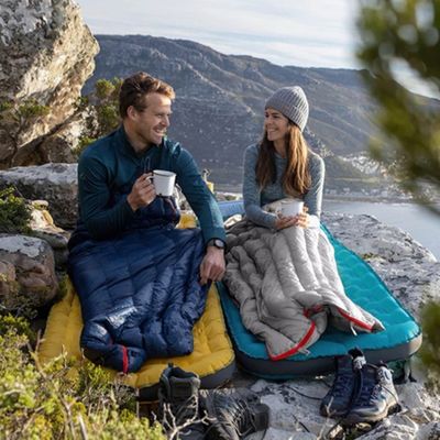 Couple prend café sac de couchage installé rocher