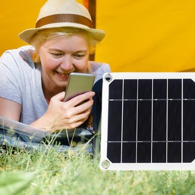 Femme allongée côté tente téléphone branche panneau solaire camping
