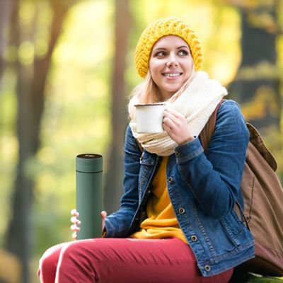 Femme assise pose randonnée gourde isotherme en main