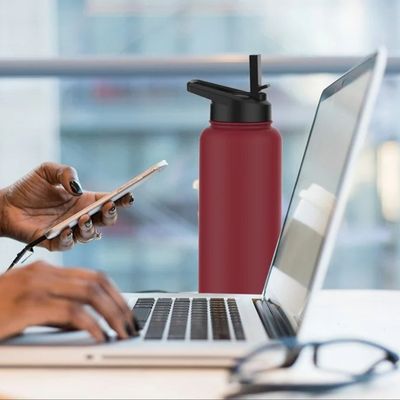 Femme au travail tasse isotherme 1l posée bureau