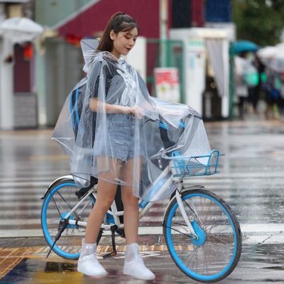 Femme avec cape de pluie vélo sur passage protégé