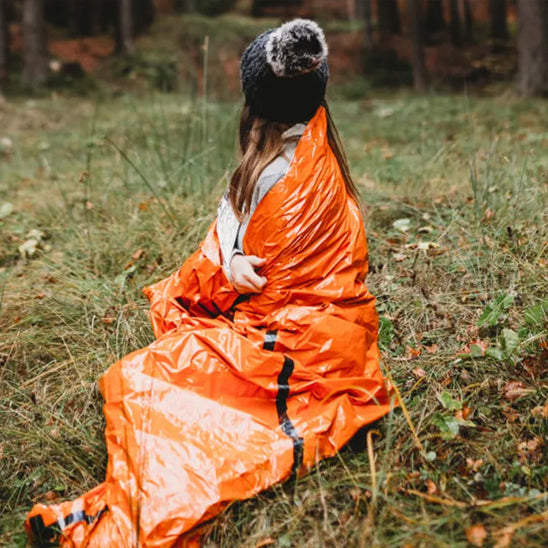 Femme dans sa couverture survie véritable bouclier thermique