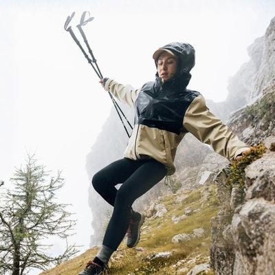 Femme descend courant rocher avec batons de randonnée