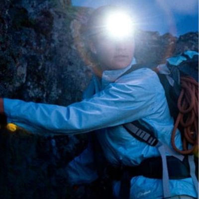 Femme escalade nocturne avec lampe frontale puissante professionnel
