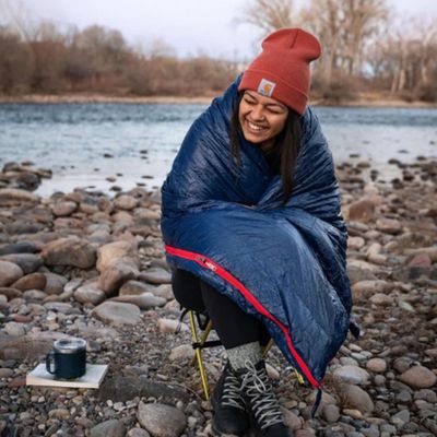 Femme heureuse assise chaise camping dans sac de couchage