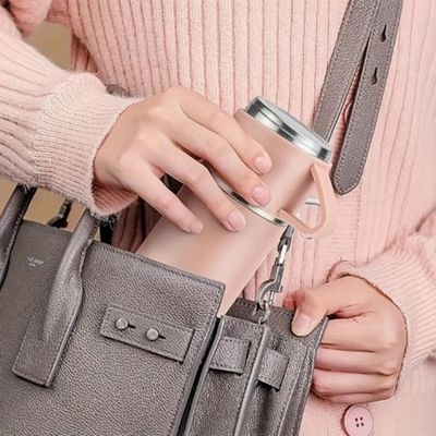 Femme insert mug thermos dans sac main