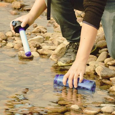 Femme remplit gourde filtrante randonnée dans ruisseau