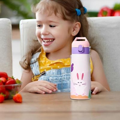 Fillette assise table avec gourde enfant inox devant fraises