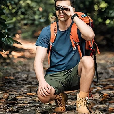 Homme accroupi bois avec jumelles pour observer les oiseaux