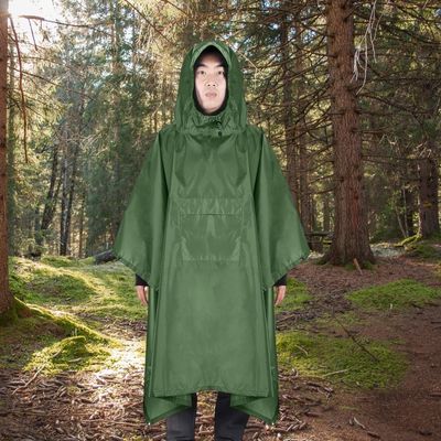 Homme avec poncho de pluie marche en forêt