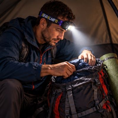 Homme bivouac range affaires sac avec lampe frontale rechargeable