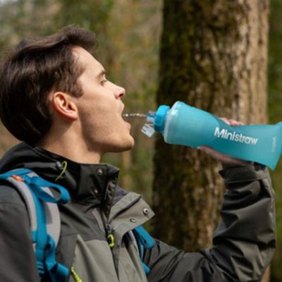 Homme boit gourde filtrante pendan trek