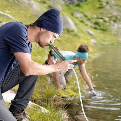 Homme boit paille pour filtrer l'eau avec prolongateur souple