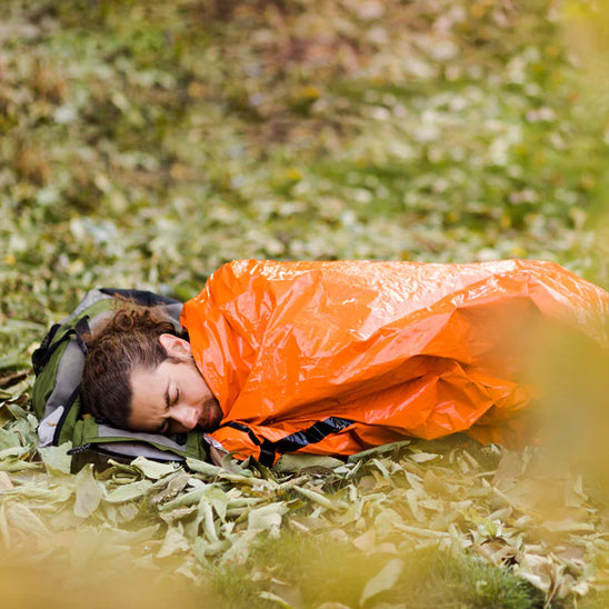 Homme dort dehors dans sa couverture survie