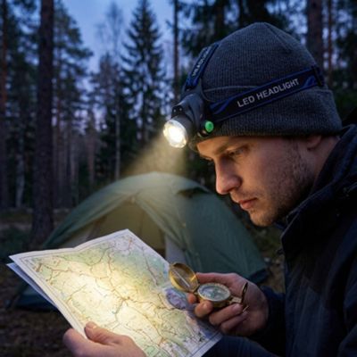Homme étudie carte bivouac avec lampe frontale LED