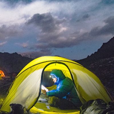 Homme lit dans tente avec lampe frontal pour trail