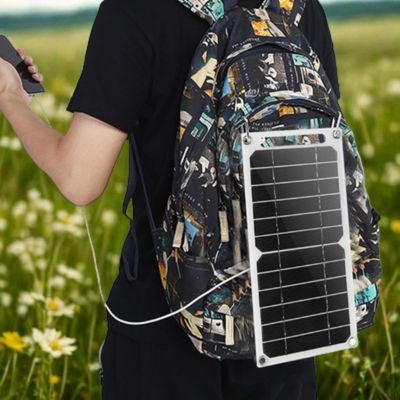 Homme marche avec panneau solaire camping fixé sur sac
