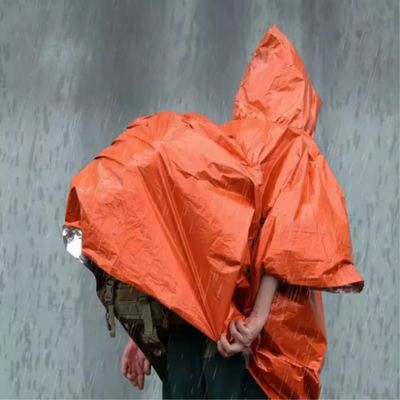 Homme nomade cape de pluie sur sac sous averse