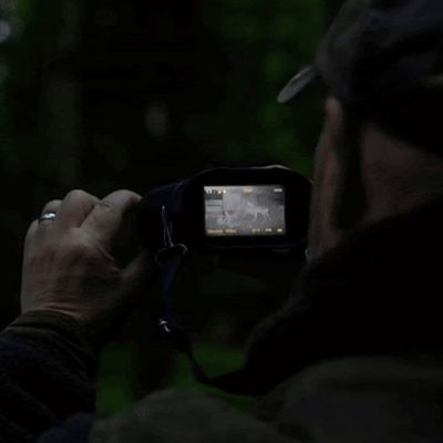 Homme observe avec jumelles à infrarouge nuit noire
