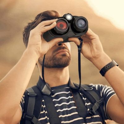 Homme observe avec jumelles à infrarouge nuit tombante