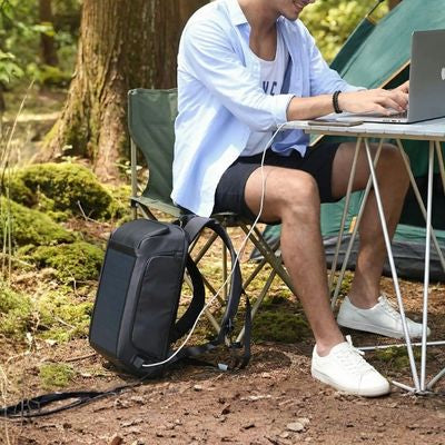 Homme pianote ordinateur sac à dos voyage recharge camping