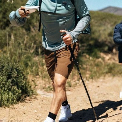 Homme regarde boussole batons de randonnée