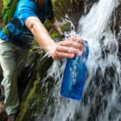 Homme remplie sa gourde filtre eau cascade ruisseau