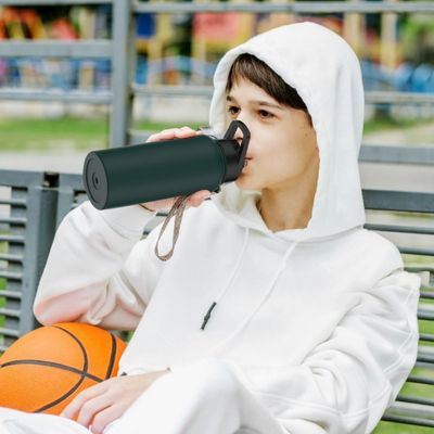 Jeune boit tasse isotherme assis sur banc