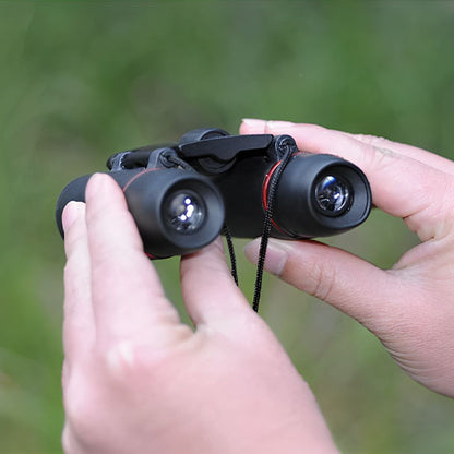 Jumelles pour observer les oiseaux BirdView tenues à deux mains, avec leur cordon