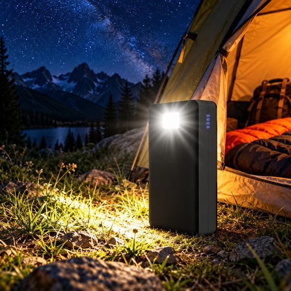 Powerbank 50000 mAh noire, lampe LED allumée devant une tente sous la Voie lactée